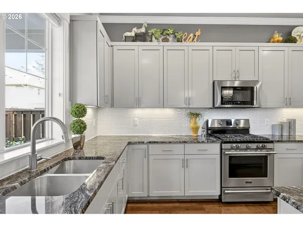 a kitchen with granite countertop a sink a stove and cabinets