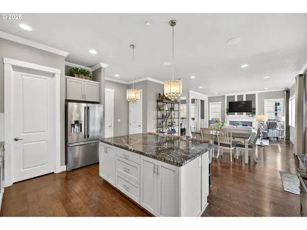 a kitchen with stainless steel appliances granite countertop a refrigerator a oven a sink and a wooden floors
