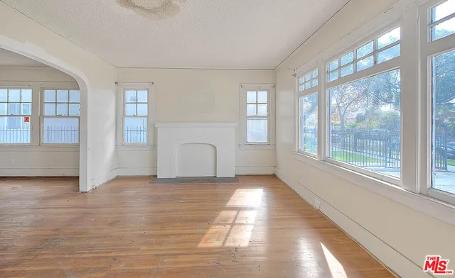 a view of an empty room with a window and wooden floor