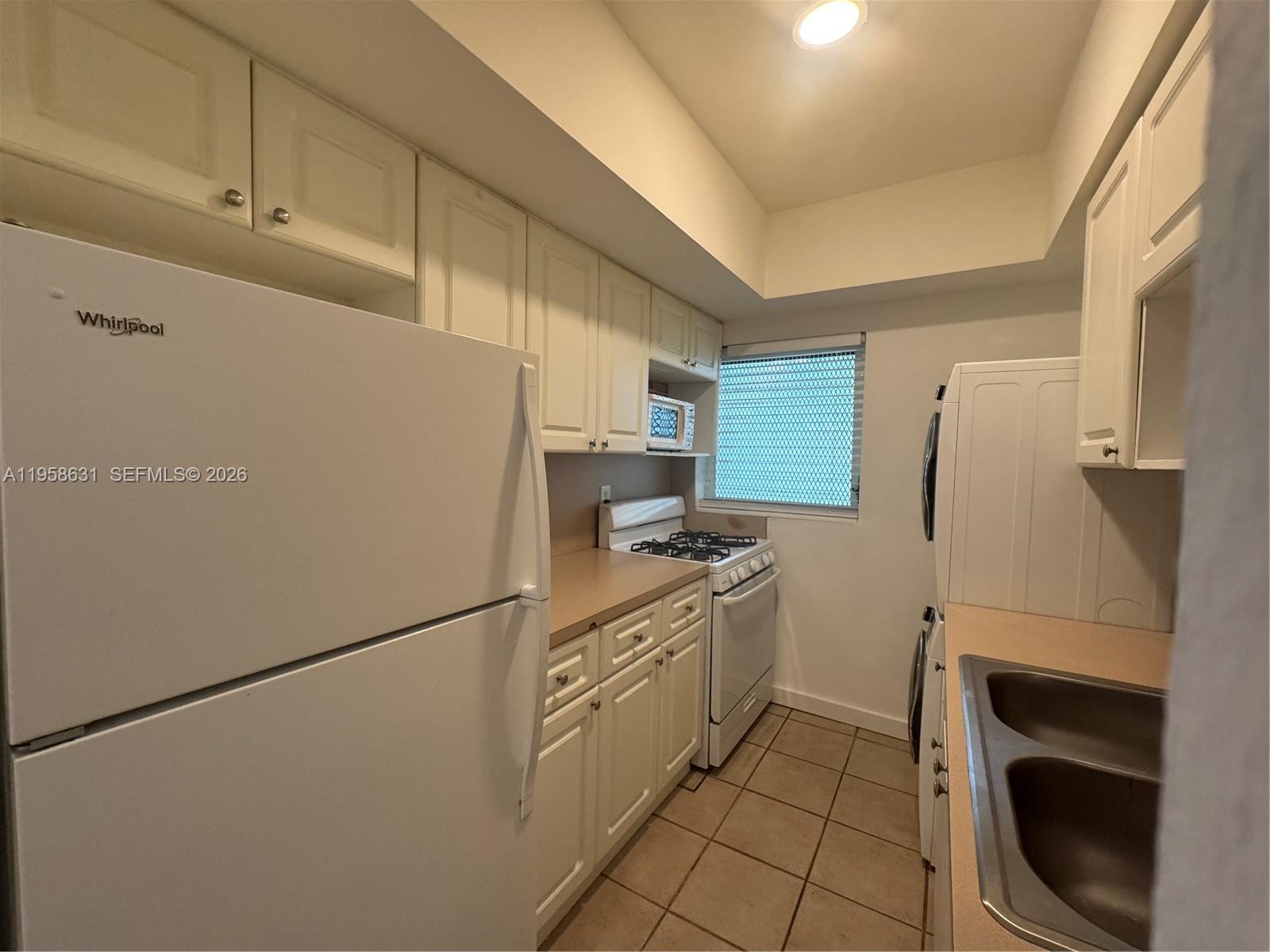 921 Meridian Avenue, Unit 7 Miami Beach, FL 33139 - Photo 18 of 33 a kitchen with a refrigerator sink stove and cabinets