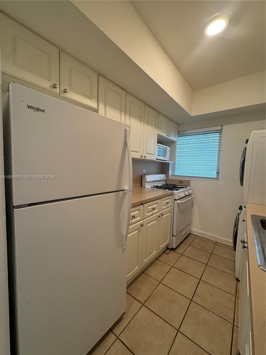 921 Meridian Avenue, Unit 7 Miami Beach, FL 33139 - Photo 20 of 33 a kitchen with a refrigerator sink stove and cabinets