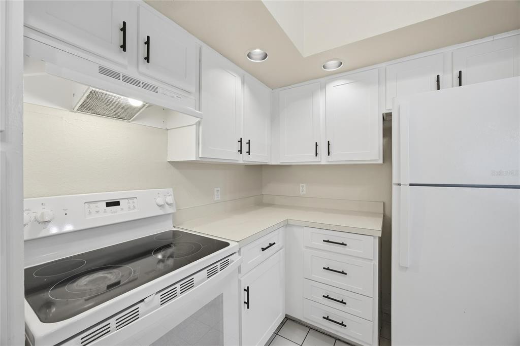 4532 Commander Drive, Unit 2132 Orlando, FL 32822 - Photo 5 of 26 a kitchen with granite countertop white cabinets and white appliances
