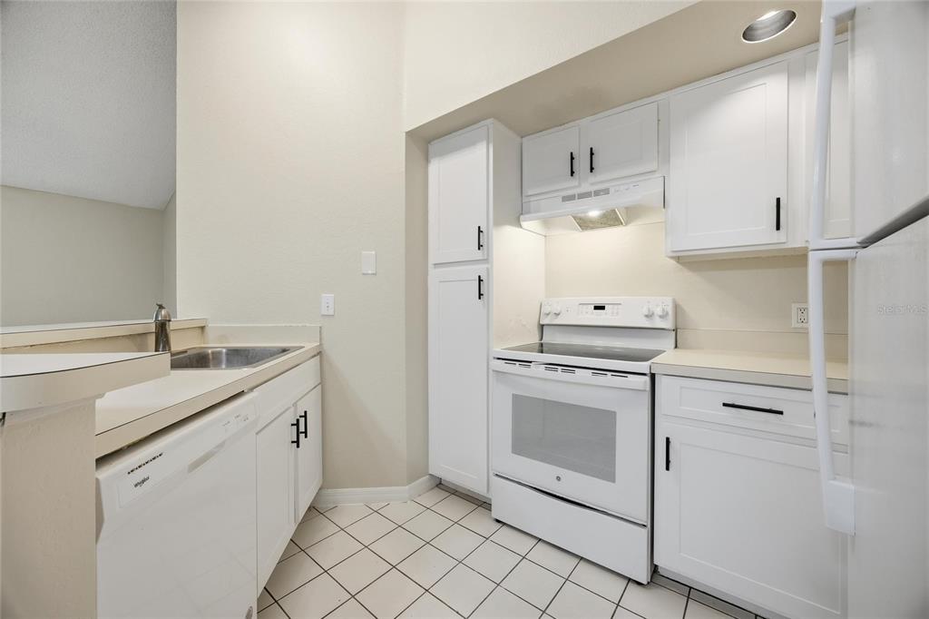 4532 Commander Drive, Unit 2132 Orlando, FL 32822 - Photo 6 of 26 a kitchen with white cabinets and white appliances