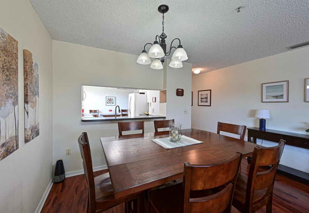 6501 Stone River Road, Unit 303 Bradenton, FL 34203 - Photo 4 of 30 a view of a dining room with furniture a chandelier and wooden floor