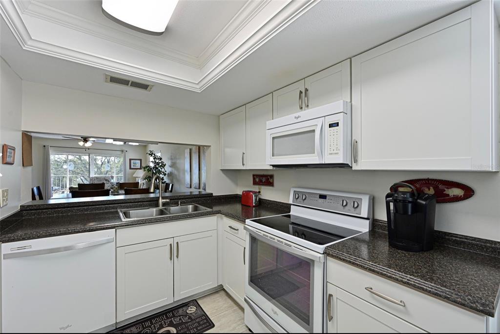 6501 Stone River Road, Unit 303 Bradenton, FL 34203 - Photo 5 of 30 a kitchen with white cabinets and appliances