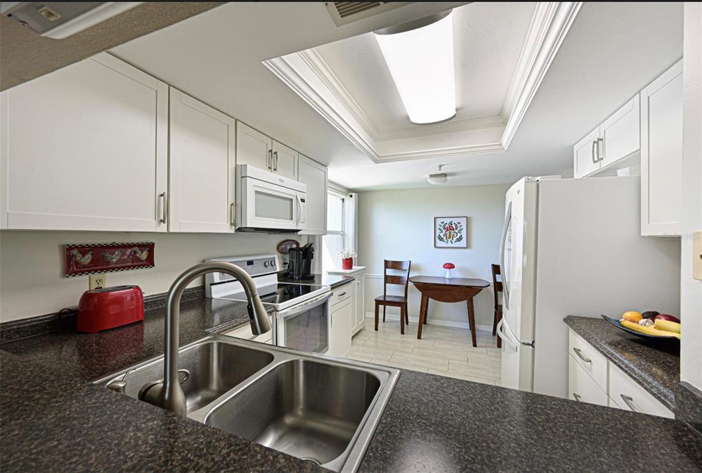 6501 Stone River Road, Unit 303 Bradenton, FL 34203 - Photo 6 of 30 a kitchen with stainless steel appliances granite countertop a sink and a refrigerator