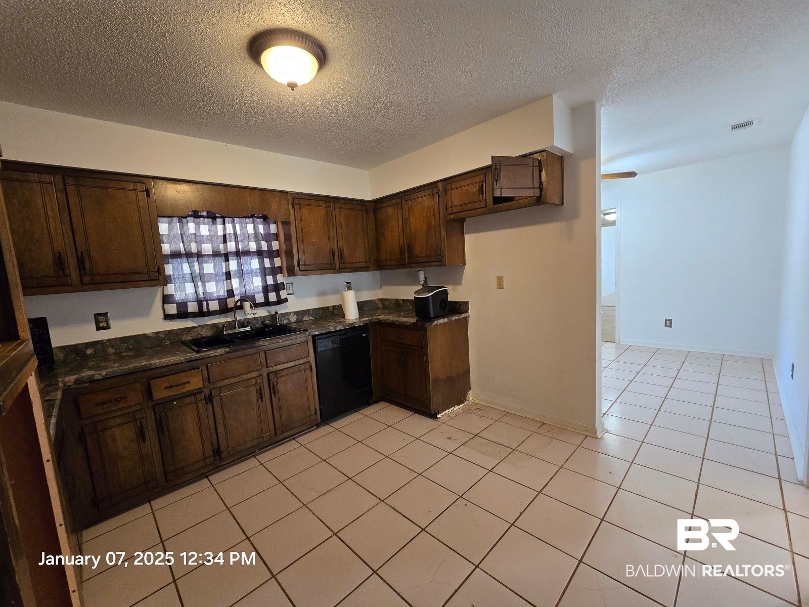 154 Byrd Road Monroeville, AL 36460 - Photo 12 of 26 Kitchen with light tile patterned flooring, dark brown cabinetry, sink, a textured ceiling, and black dishwasher