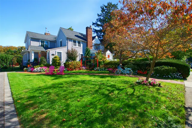 a front view of a house with a yard and a large tree