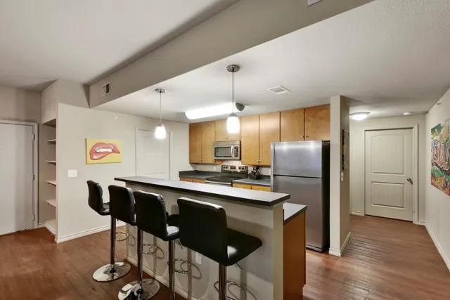 a kitchen with stainless steel appliances a dining table chairs refrigerator and sink