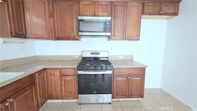 a kitchen with granite countertop a stove top oven microwave and cabinets