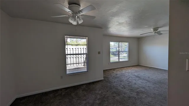 an empty room with windows and ceiling fan