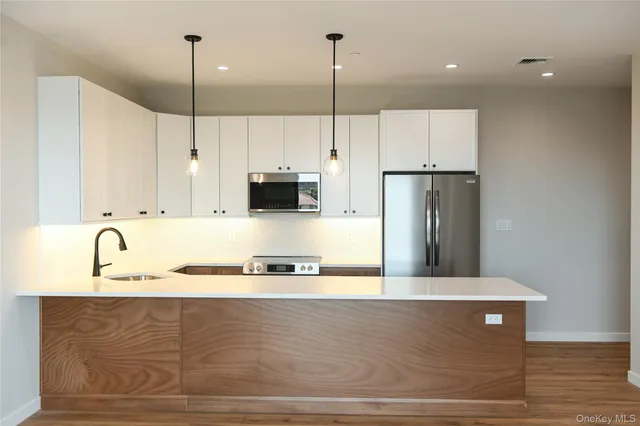 a kitchen with stainless steel appliances granite countertop a sink a stove and a wooden floors