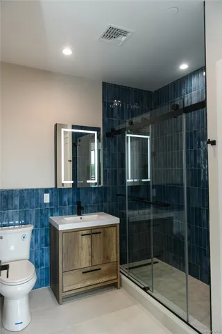 a bathroom with a sink a toilet a mirror and shower