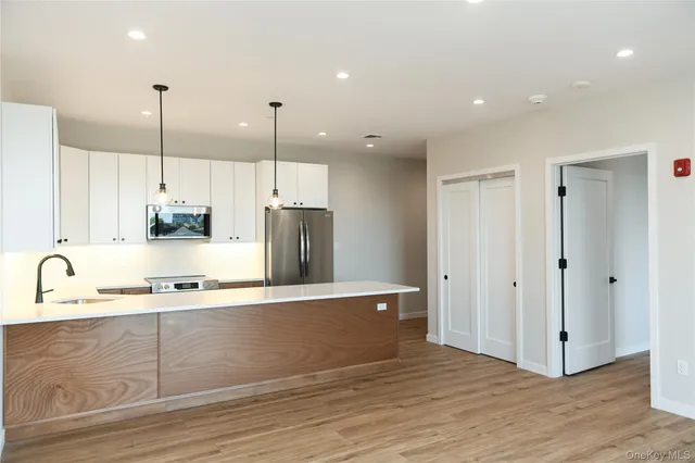 a kitchen with stainless steel appliances granite countertop a sink a refrigerator and a wooden floor