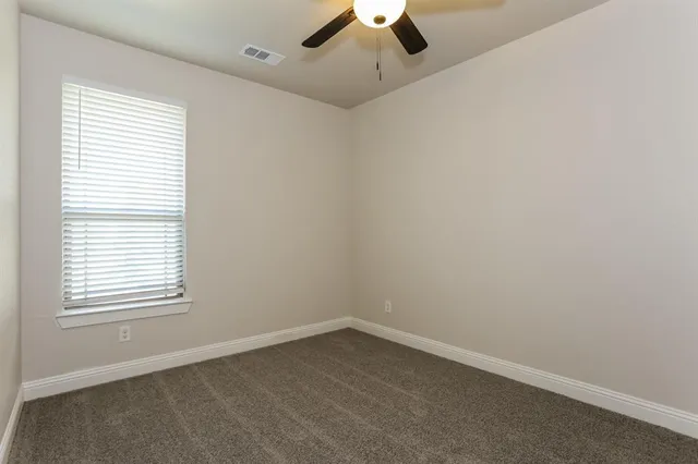 an empty room with a window and a fan