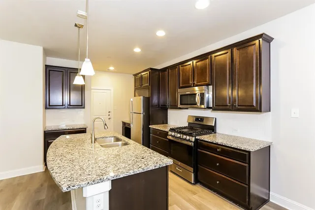 a kitchen with granite countertop cabinets stainless steel appliances and wooden floor