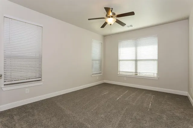 an empty room with windows and fan