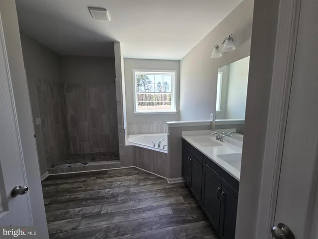 a bathroom with a granite countertop sink and mirror with bathtub