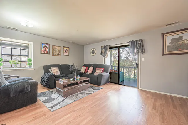 a living room with furniture large window and wooden floor
