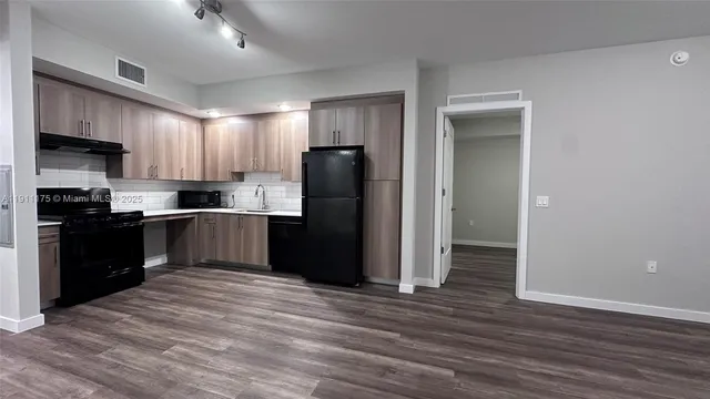 a kitchen with granite countertop wooden floors stainless steel appliances and a sink