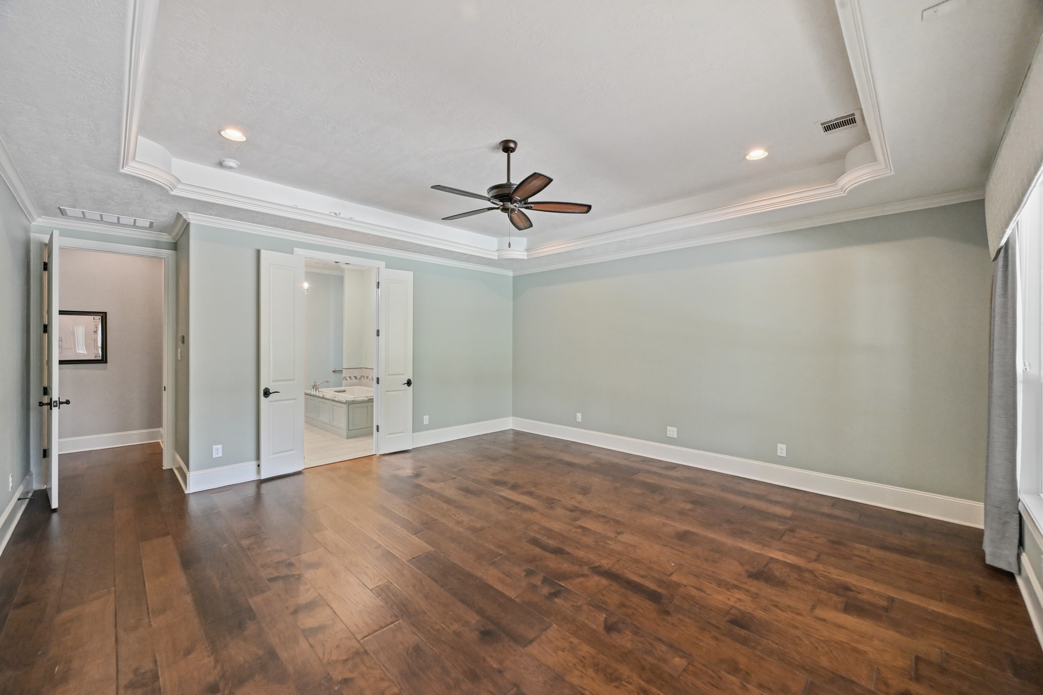 27322 Silver Jade Court Spring, TX 77386 - Photo 14 of 45 Primary bedroom features a tray ceiling, ceiling fan, crown molding, wood flooring, an ensuite bath, and a spacious walk-in closet with direct access to the laundry room for added convenience.
