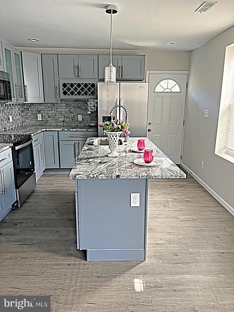 a kitchen with kitchen island granite countertop a stove a sink and white cabinets