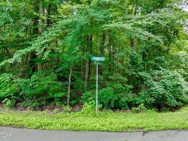 an aerial view of residential house with outdoor space and trees all around