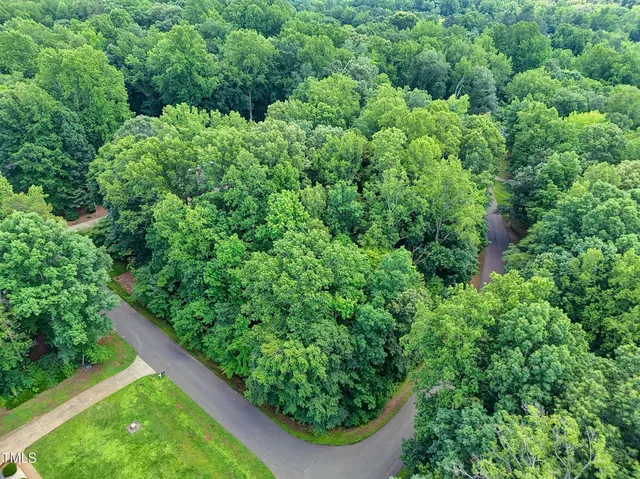 an aerial view of residential house with outdoor space and trees all around