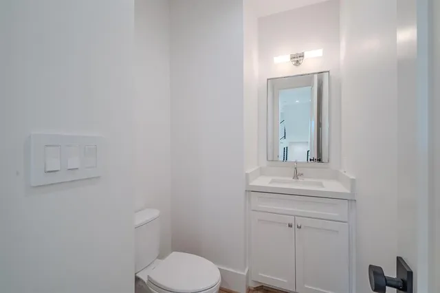 a bathroom with a toilet a sink a mirror and vanity