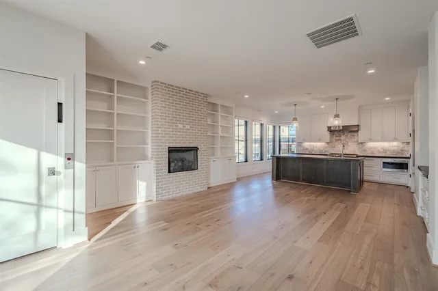 a view of kitchen with kitchen island wooden floor and stainless steel appliances