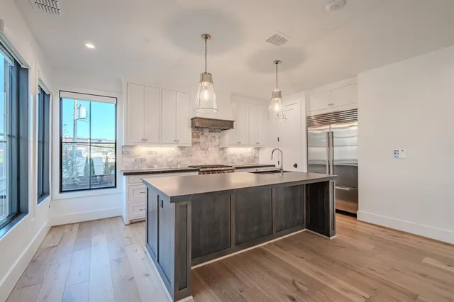 a kitchen with stainless steel appliances granite countertop a sink a stove and a wooden floors