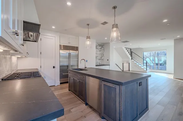 a kitchen with stainless steel appliances granite countertop a sink a stove and a wooden floors