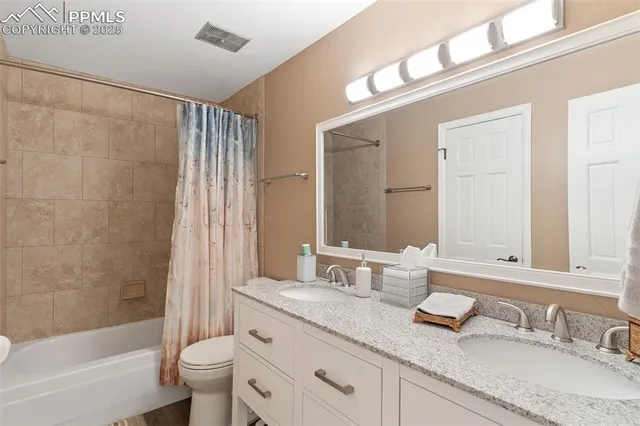 a bathroom with a granite countertop sink a toilet and a large mirror