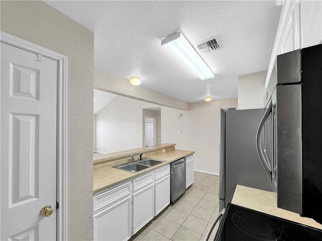 14302 Cruiser Street, Unit A Corpus Christi, TX 78418 - Photo 12 of 28 a large kitchen with a refrigerator and a sink