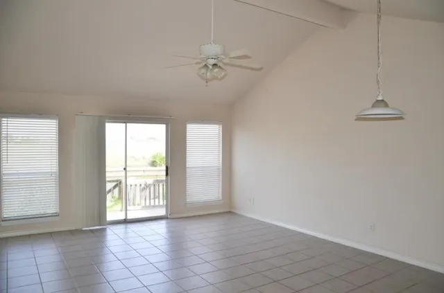 an empty room with chandelier fan and windows