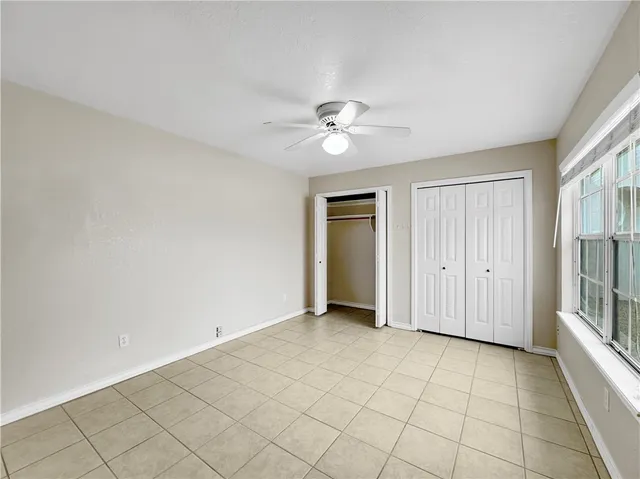 an empty room with windows and fan