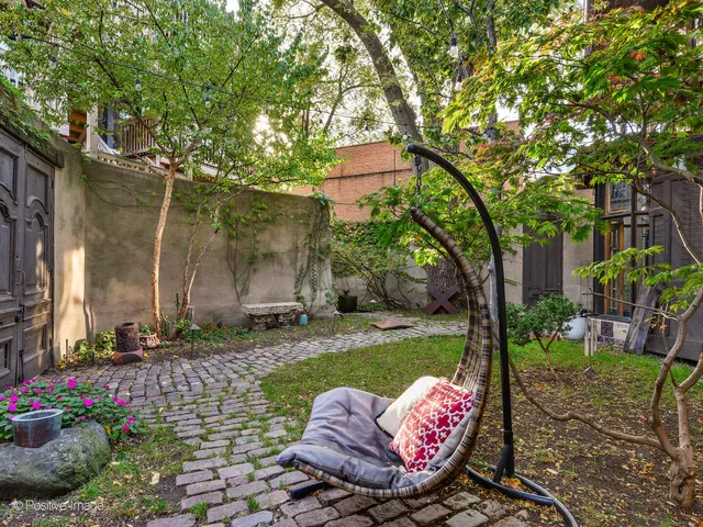 a view of a backyard with table and chairs potted plants and large tree