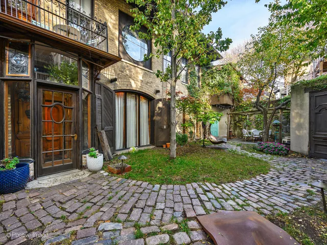 a view of a brick house with a chairs and table in a patio