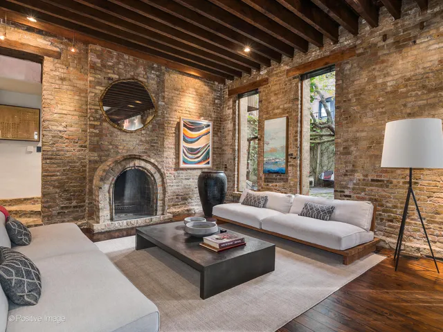 a living room with couches a fireplace and a dining table with wooden floor