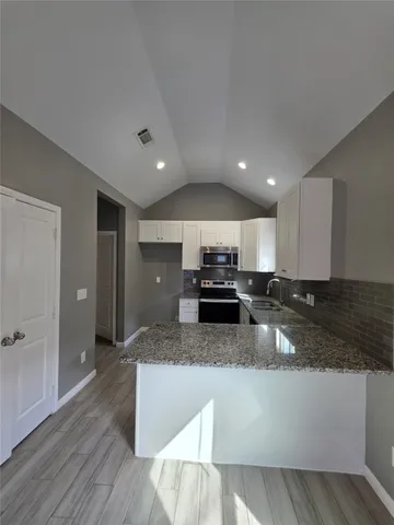 a kitchen with stainless steel appliances granite countertop a sink a stove and a refrigerator