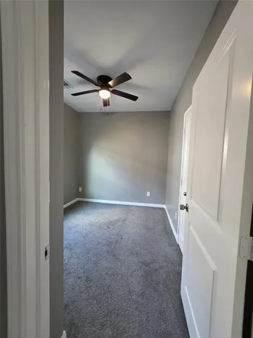 an empty room with a ceiling fan and a window