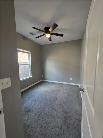 an empty room with windows and fan