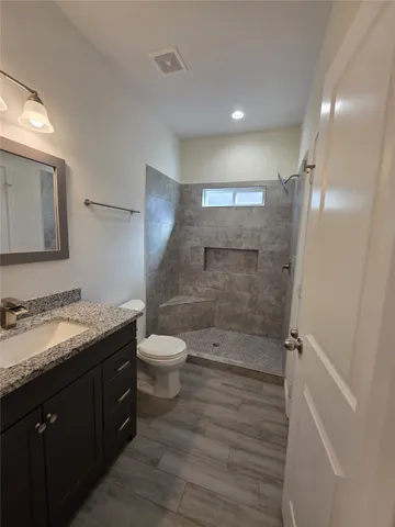 a bathroom with a granite countertop sink toilet and shower