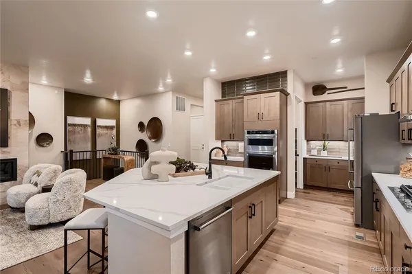 a kitchen with stainless steel appliances granite countertop a refrigerator a stove a sink a dining table and chairs