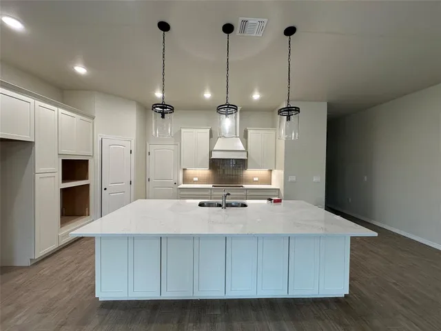 a large kitchen with stainless steel appliances a large counter top a stove a sink and a refrigerator