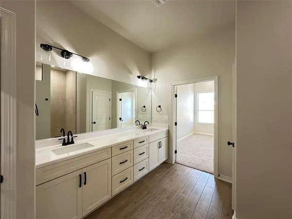 a spacious bathroom with a double vanity sink a large mirror and shower