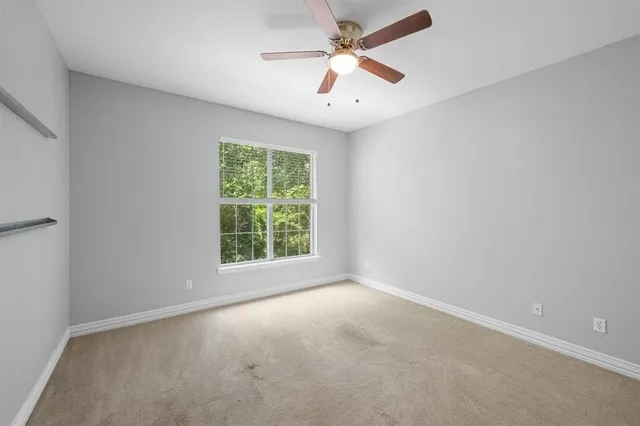 an empty room with a window and a fan