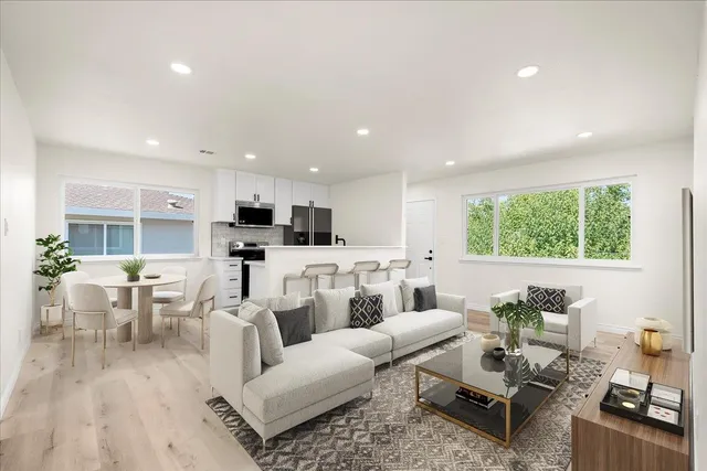 a living room with furniture kitchen view and a large window