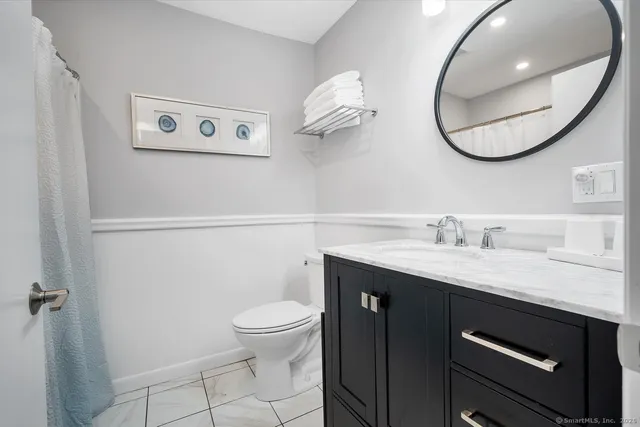 a bathroom with a granite countertop toilet sink and mirror