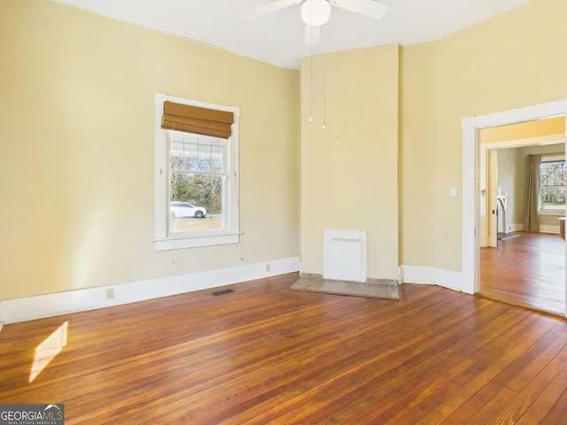 a view of an empty room with wooden floor and a window